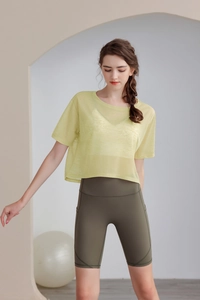 Dettaglio maglietta da yoga verde chiaro ampia e pantaloncini da ciclista verde oliva