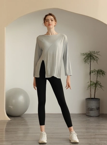 Détail du haut de yoga gris clair à manches longues avec fente latérale et tissu respirant