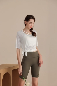 Detail of white tencel yoga top featuring an asymmetric neck cutout and side tie knot