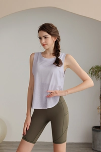 Dettaglio del tessuto della canotta sportiva lilla e dei pantaloncini fitness a vita alta