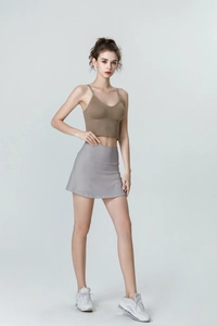 Close-up of light grey high-waisted tennis skirt with built-in shorts and brown crop top