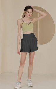Detail der High-Waist Sport-Shorts mit Seitentasche und avocado-grünem Tanktop