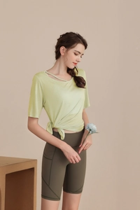 Detail of light green yoga top with asymmetric cutout neckline and side knot hem design