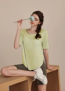 Detail view of light green yoga top featuring cross-neckline and curved hem slim design