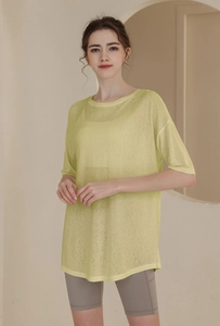 Close-up of pale yellow semi-transparent loose fit t-shirt with curved hem for sports