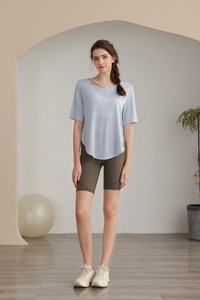 Detail view of light blue tencel yoga top paired with olive green sports shorts and sneakers