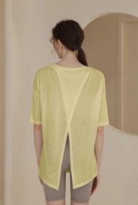Detailed back view of light yellow sports top featuring a cross open back design