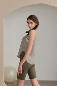 Dettaglio della canotta da yoga ampia con spacchi laterali e texture a maglia traspirante