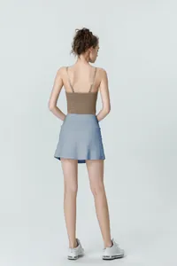 Rear view of a light blue pleated tennis skort paired with a brown ribbed tank top