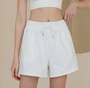 Detailed view of white high-waisted sports shorts featuring elastic waistband and metal drawstrings