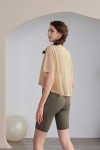 Dettaglio del top da yoga in rete e pantaloncini da ciclista verde oliva a vita alta con tasche