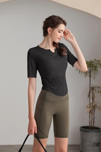 Détail du col en V et du plissé latéral sur un t-shirt de yoga noir ajusté
