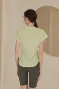 Rear view of breathable yellow workout tee with curved hem and olive green biker shorts