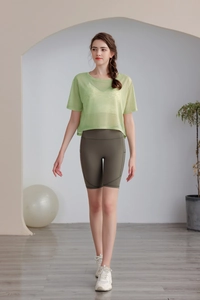Dettaglio del top da yoga in mesh verde chiaro e degli shorts a vita alta oliva