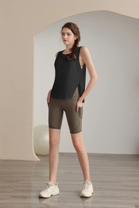 Dettaglio del gilet sportivo nero con spacco laterale e pantaloncini da yoga oliva