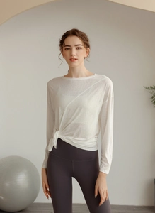 Détail du haut de yoga blanc à manches longues avec un nœud latéral élégant sur le côté