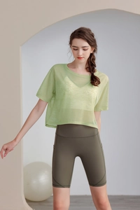 Dettaglio della maglia da yoga verde chiaro ampia con pantaloncini fitness color oliva