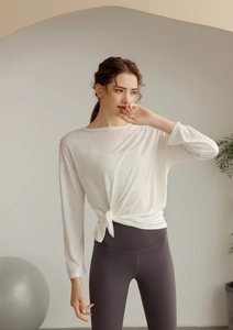 Détail du haut de yoga blanc semi-transparent avec nœud et legging gris à taille haute