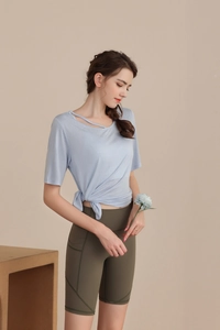 Detail of light blue yoga top with knot hem and olive high waist biker shorts with pockets