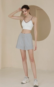 Female model in loose nylon shorts with drawstring and sneakers in minimalist studio