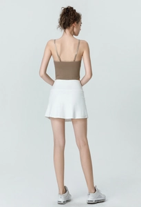 Rear view of brown knit tank top and white high-waisted tennis skirt with running shoes