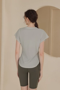 Rear view of light sage green workout t-shirt with curved hem and olive gym shorts