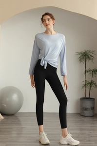 Détail du haut de yoga bleu clair à manches longues noué et legging noir taille haute