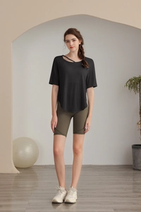 Side view of woman in black t-shirt and olive green high-waist fitness shorts in studio