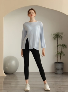 Détail du haut de yoga bleu clair à manches longues fendu et leggings noirs taille haute
