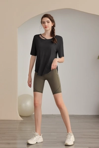 Detail of black asymmetric one-shoulder yoga tee and olive green high-waist biker shorts
