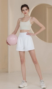 Detail of high-waist loose sports shorts and beige yoga bra with a pink exercise ball