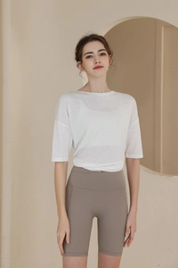 Detail of white semi-transparent t-shirt and beige high-waisted yoga shorts set