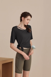 Detail of slim-fit yoga top with cutout neckline and knotted waist in black