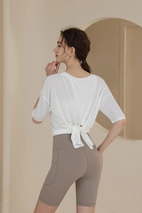 Rear view of white tie-back fitness top and taupe yoga shorts with practical side pockets