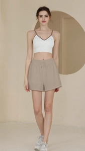 Close-up of beige loose gym shorts with drawstring waist and breathable fabric texture