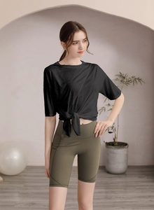 Détail du haut de yoga noir noué et du short cycliste taille haute vert olive
