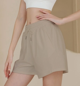 Detail of beige high-waist athletic shorts featuring adjustable drawstring and side pockets