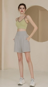 Detailansicht von hellgrünem Sport-BH und lockeren grauen Yoga-Shorts mit hoher Taille