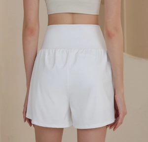 Detail view of high-waisted white yoga shorts with elastic waistband and pleated back detail