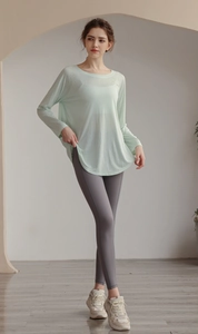 Relaxed yoga top with grey leggings and off-white sneakers in a bright studio