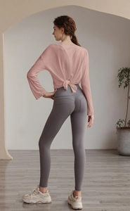 Detail view of the back knot design on a pink long sleeve yoga top with open back style