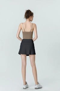 Back view of a model wearing a brown ribbed crop top and a black A-line sports skirt