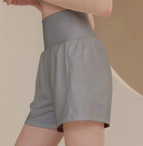 Close-up of the high-waisted compression band and loose fit on light grey gym shorts