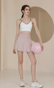 Dettaglio della gonna da tennis rosa e canotta sportiva bianca indossata da una modella