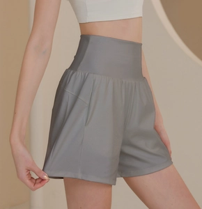 Detail view of high-waisted sage green sports shorts with wide leg and side pockets