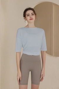 Detail of light blue yoga top fabric texture and loose fit design on a female model