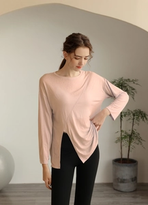 Détail du haut de yoga rose clair avec tissu respirant et ourlet fendu asymétrique