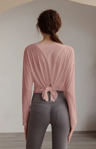Detail view of pink yoga cover up with open tie-back design and grey gym leggings