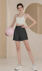 Close-up of black high-waisted nylon sports shorts and beige yoga bra on a female model