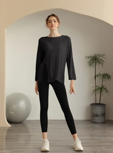 Détail du haut de yoga ample noir à manches longues avec fente latérale et tissu respirant